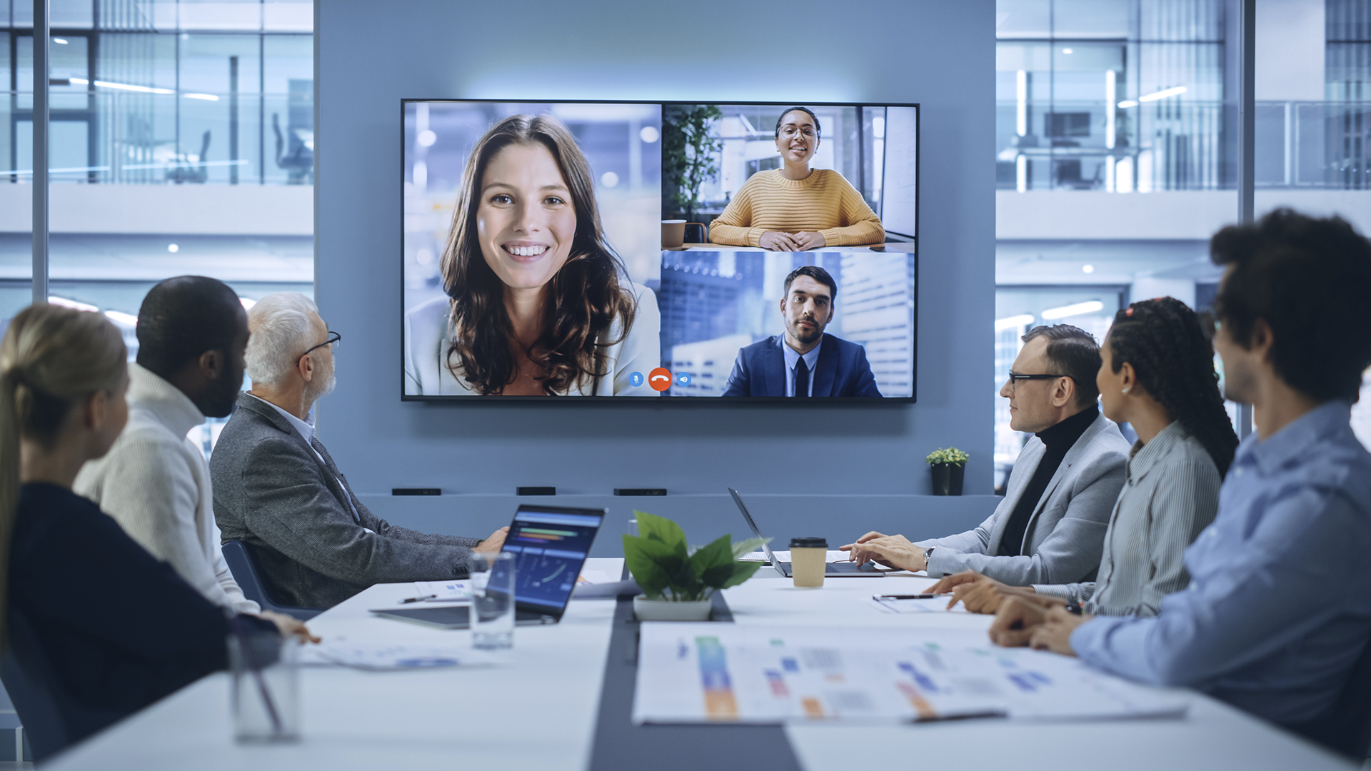 Equipe em reunião, algumas pessoas presencial e outras em home office